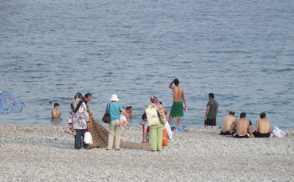 Turecká rodina na pláži: koberec a všetko potrebné v igelitkách.